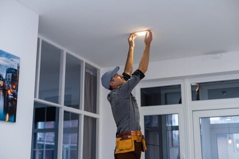 An electrician is installing spotlights on the ceiling.